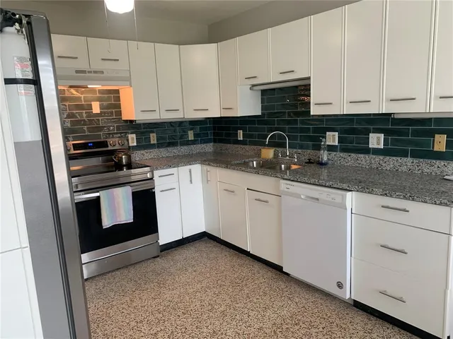 a kitchen with granite countertop white cabinets and stainless steel appliances