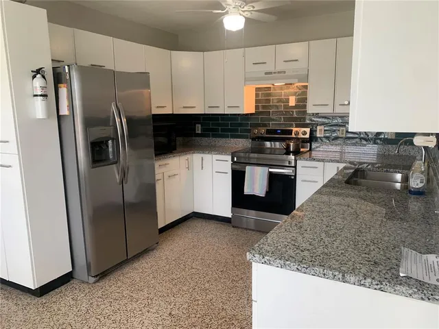 a kitchen with stainless steel appliances granite countertop a refrigerator a stove and a sink