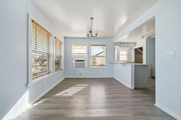 an empty room with wooden floor cabinet and windows