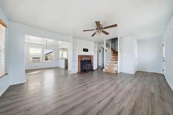 an empty room with wooden floor fireplace and windows