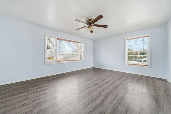 a view of empty room with wooden floor and fan