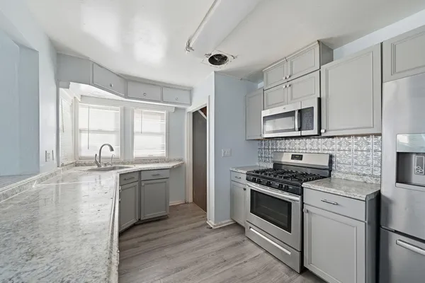 a kitchen with granite countertop a sink stove and cabinets