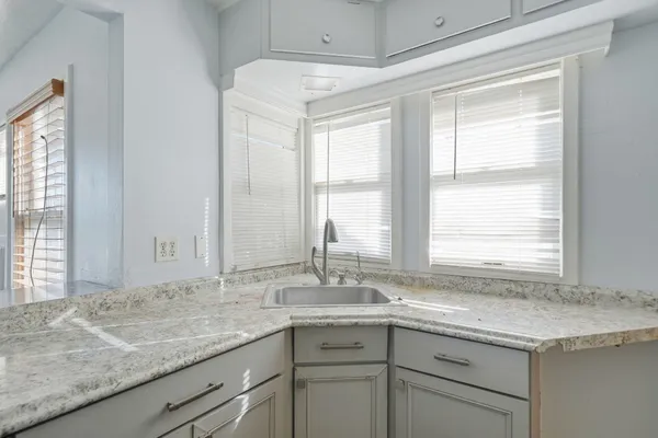 a bathroom with a granite countertop sink and a window