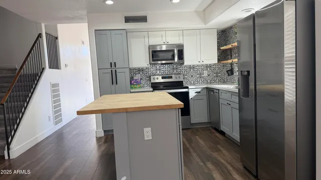 a kitchen with stainless steel appliances granite countertop a refrigerator and a stove top oven