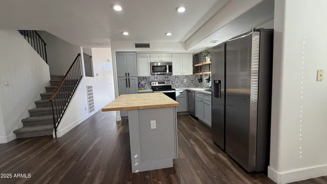a view of a livingroom with wooden floor a ceiling fan and windows