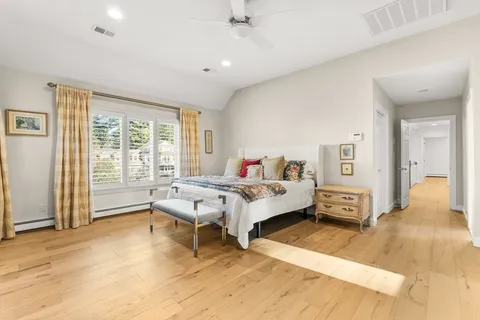 a spacious bedroom with a bed and wooden floor