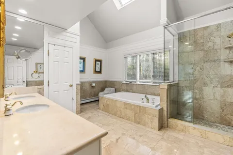 a spacious bathroom with a tub sink and mirror