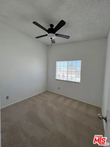 an empty room with windows and fan