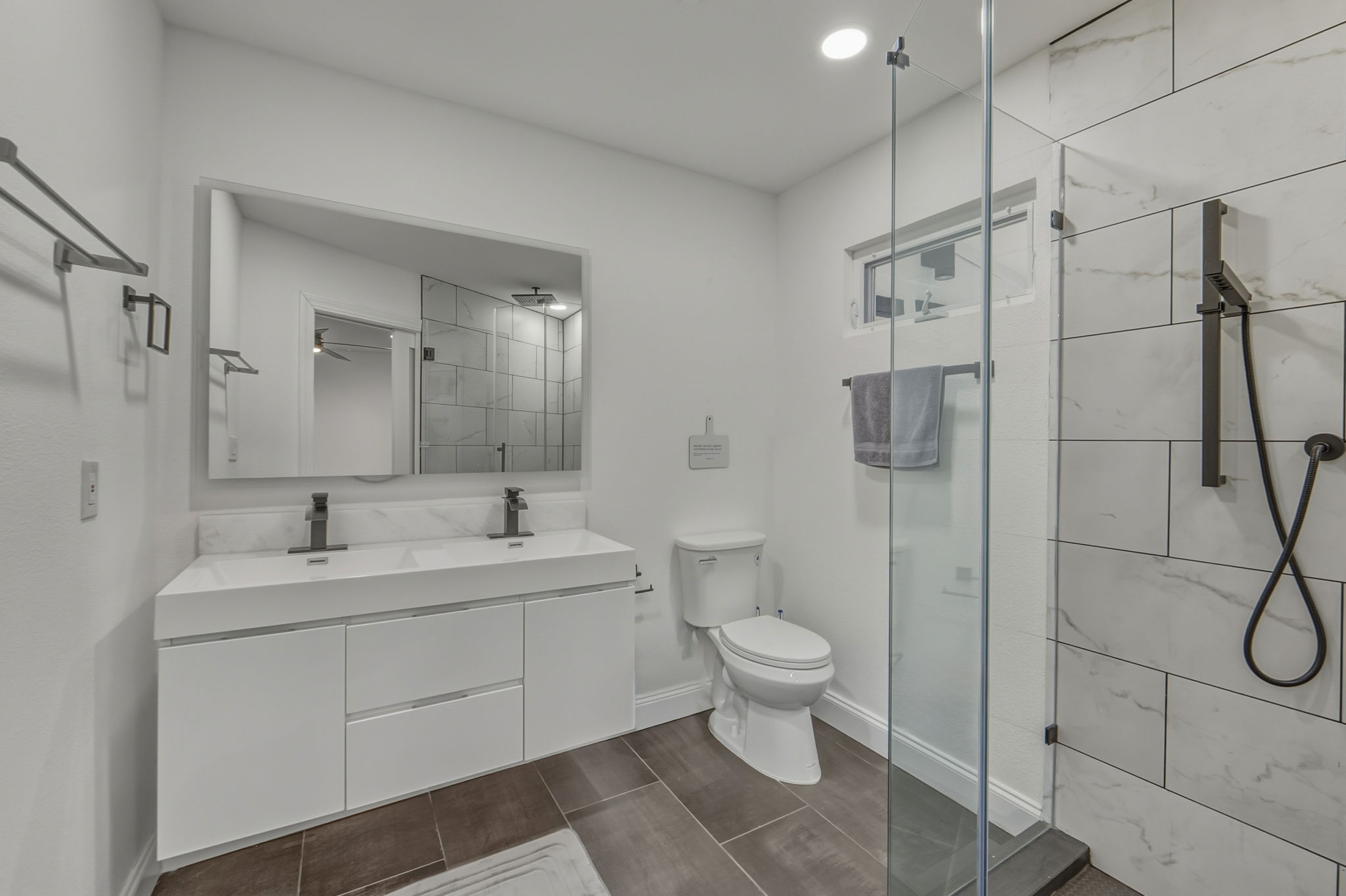 2107 Lewood Circle Austin, TX 78745 - Photo 11 of 30 Full bath featuring a stall shower, double vanity, and dark tile patterned flooring
