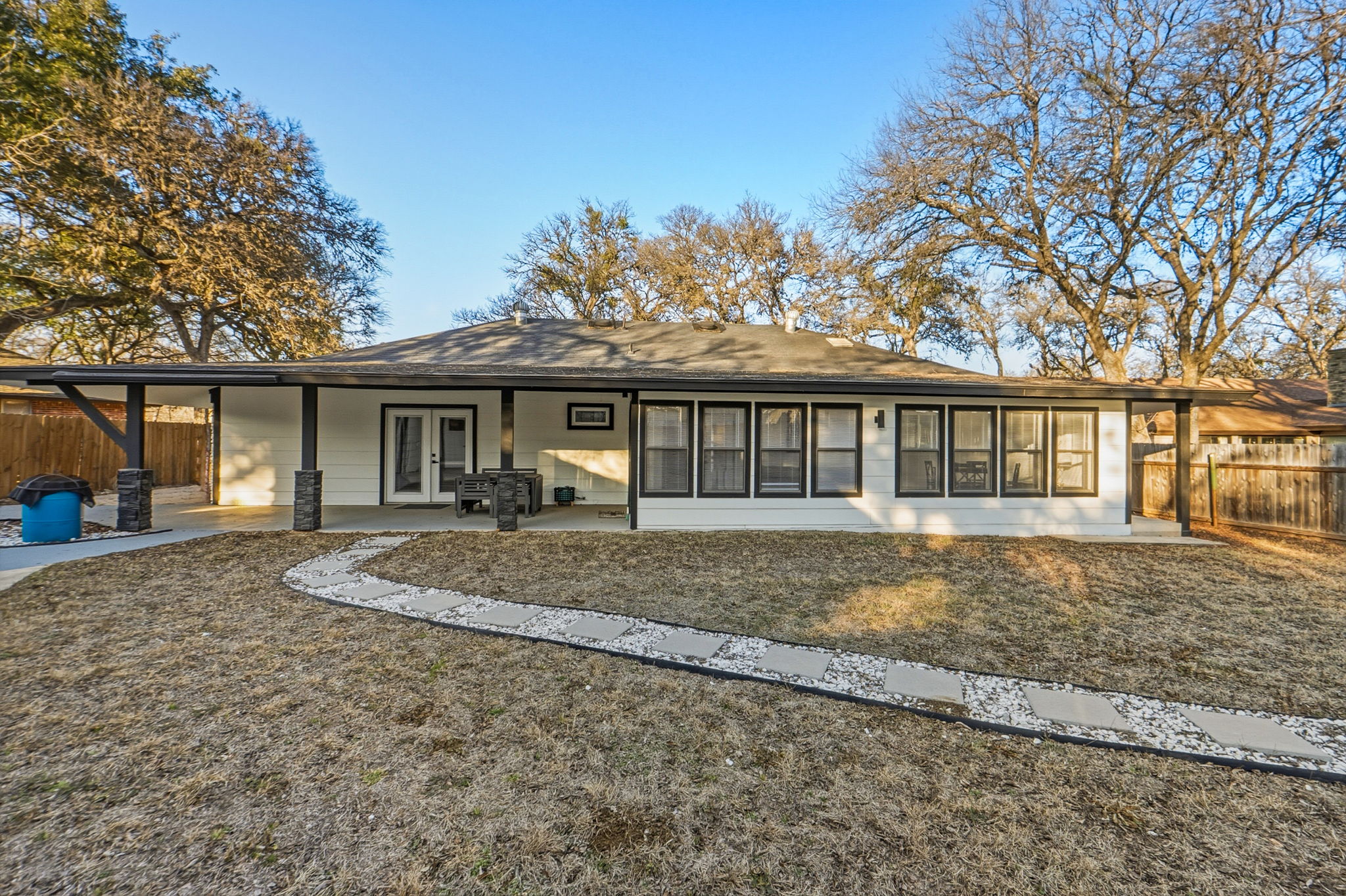 2107 Lewood Circle Austin, TX 78745 - Photo 27 of 30 Rear view of house with french doors, an attached carport, a sunroom, a patio area, and roof with shingles