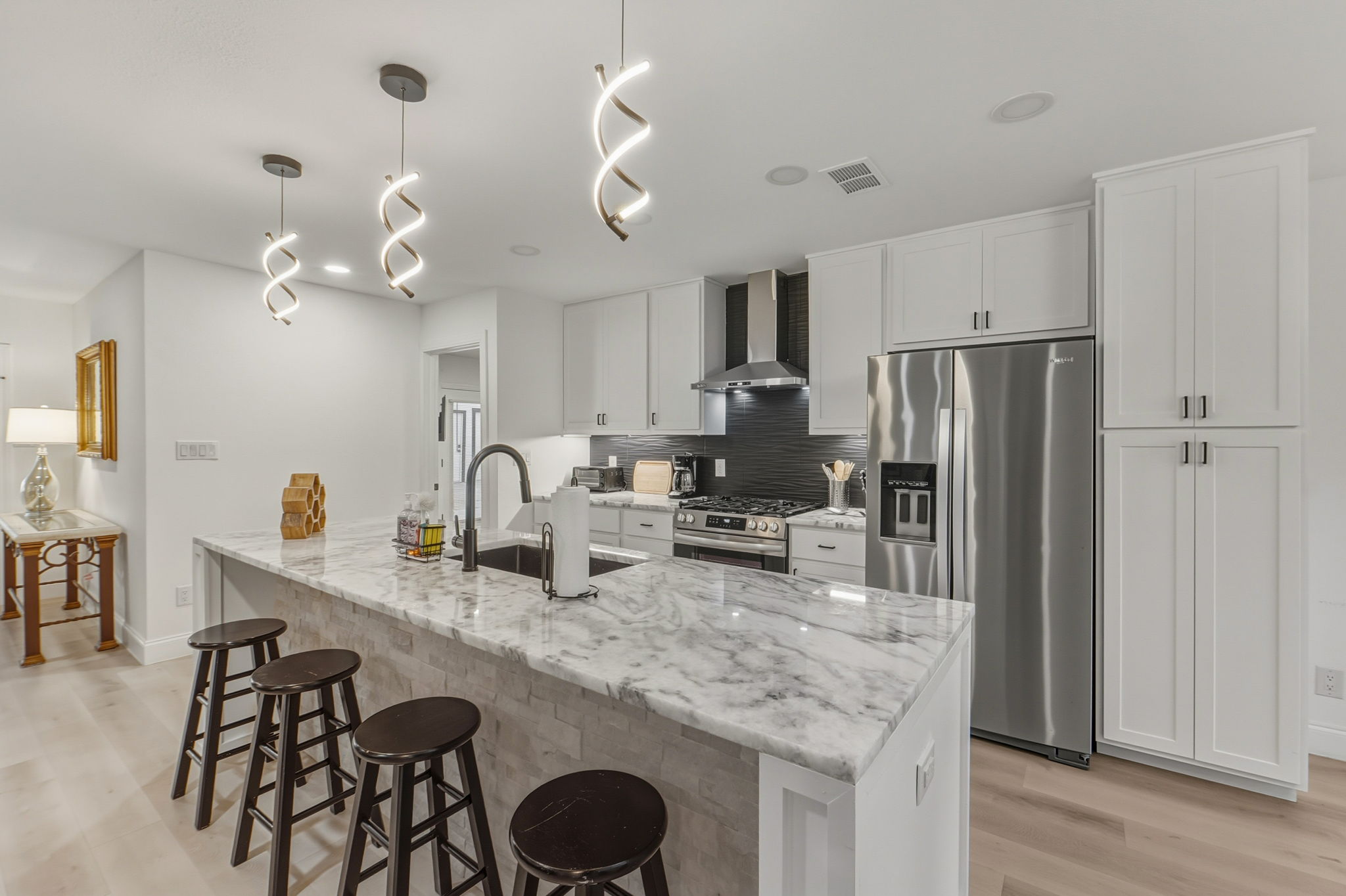 2107 Lewood Circle Austin, TX 78745 - Photo 8 of 30 Kitchen featuring stainless steel appliances, light stone counters, light wood-style flooring, and white cabinetry