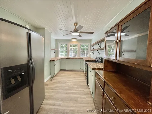 a kitchen with stainless steel appliances granite countertop a refrigerator a sink dishwasher a stove and white countertops with wooden floor