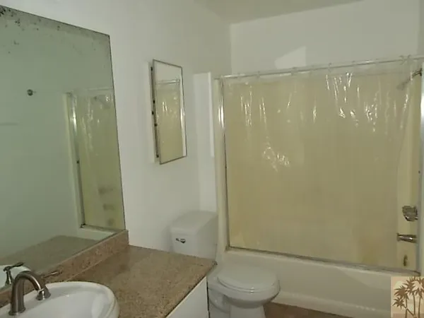 a bathroom with a granite countertop bathtub shower sink vanity and toilet