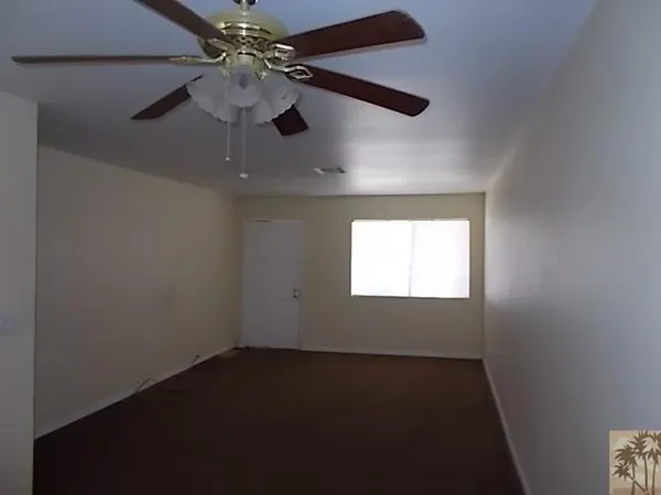 an empty room with a window and a fan