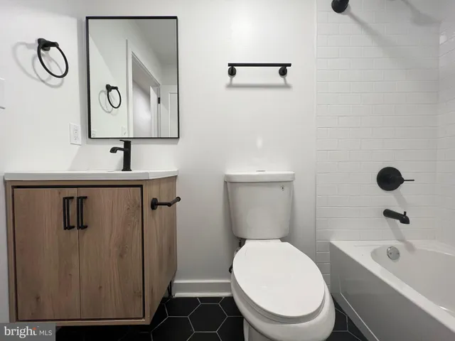 a bathroom with a toilet sink vanity tub and mirror