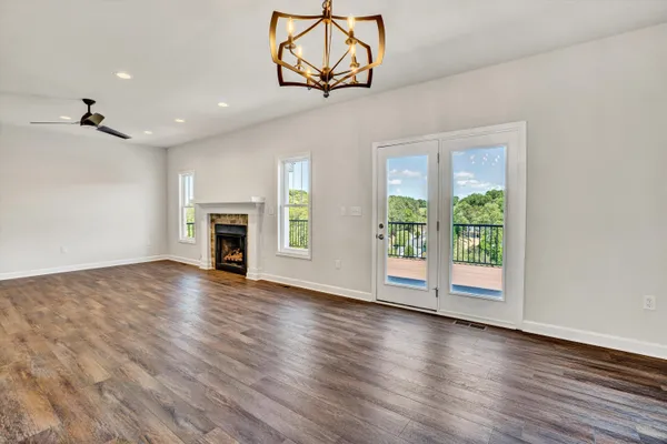 an empty room with wooden floor fireplace and windows
