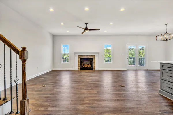 an empty room with wooden floor fireplace and windows