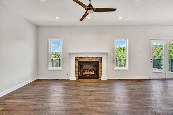 an empty room with wooden floor a fireplace and windows