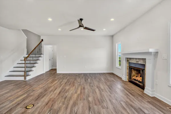 a view of an empty room with wooden floor fireplace and a window