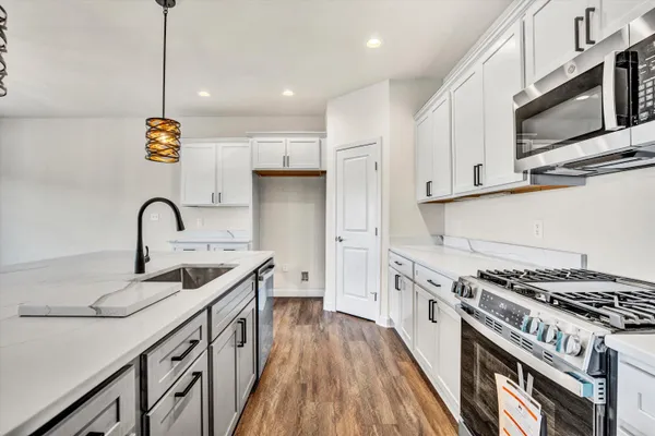 a kitchen with stainless steel appliances granite countertop a sink a stove and a wooden floors