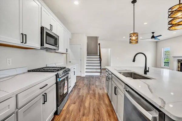 a kitchen with stainless steel appliances granite countertop a sink a stove and a wooden floors