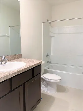 a bathroom with a granite countertop sink a toilet and a bathtub