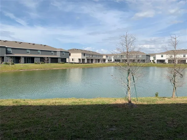 a view of a lake with a big yard and large trees