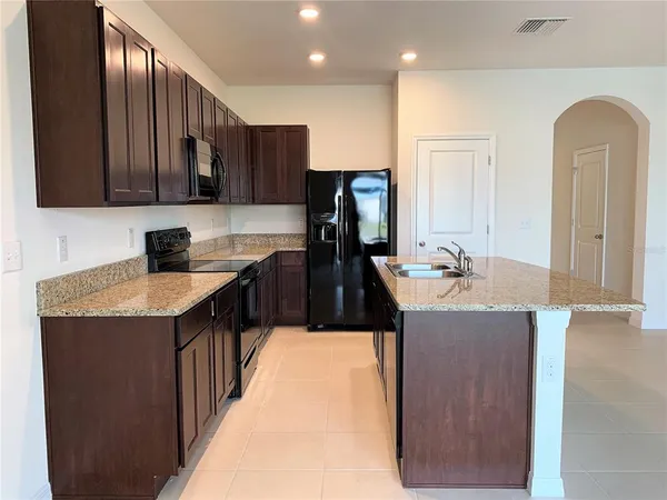 a kitchen with kitchen island granite countertop a sink a counter top space and stainless steel appliances