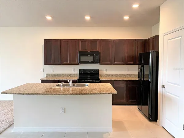 a kitchen with kitchen island granite countertop stainless steel appliances stove microwave and refrigerator