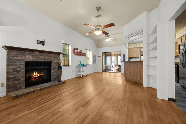 a view of an empty room with wooden floor fireplace and a window