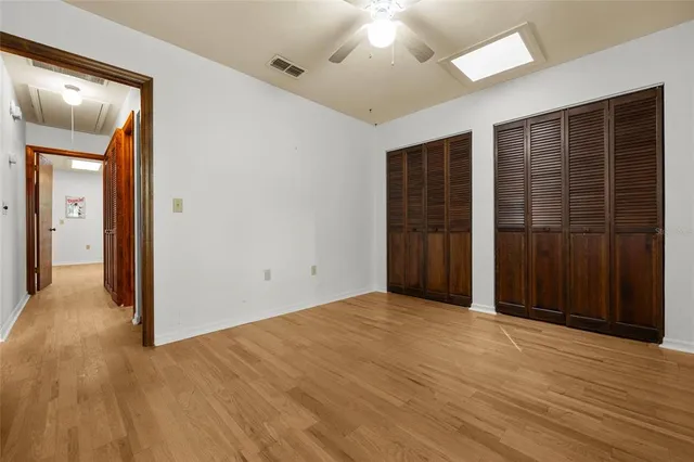 a view of an empty room with wooden floor and closet