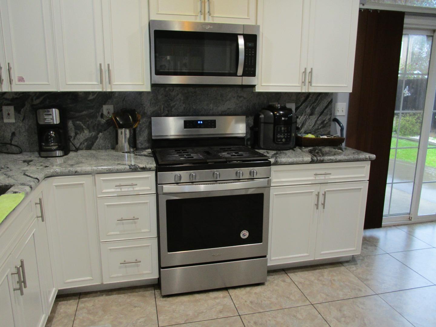 413 Hydrangea Court Merced, CA 95341 - Photo 3 of 16 a kitchen with white cabinets and appliances