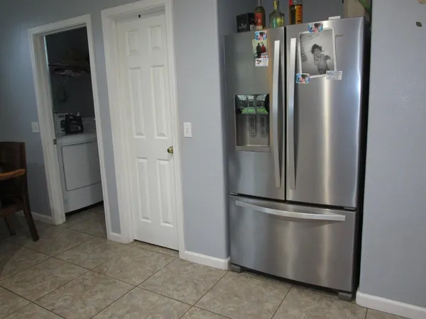 a view of a refrigerator in kitchen and an empty room