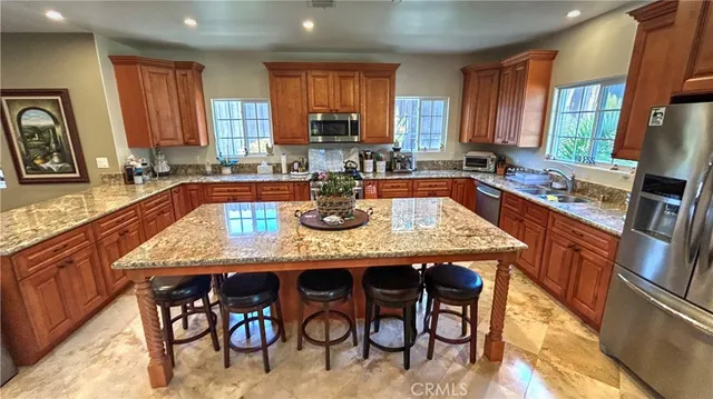 a kitchen with stainless steel appliances granite countertop table chairs sink and cabinets