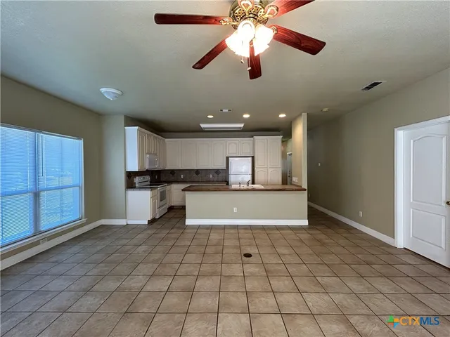 a view of an empty room and kitchen view