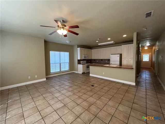 a view of an empty room and kitchen view