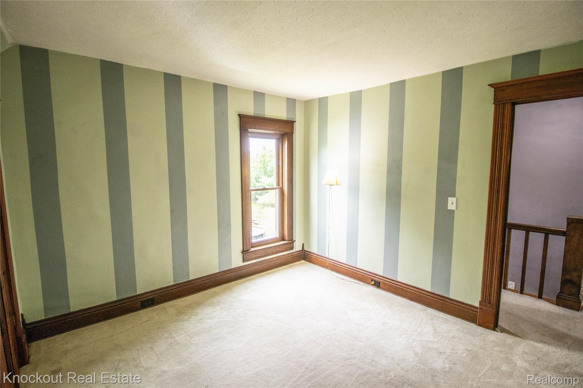 19983 West Ridge Road Henderson, MI 48841 - Photo 40 of 76 Room featuring striped walls, light-colored carpeting, and dark wood trim