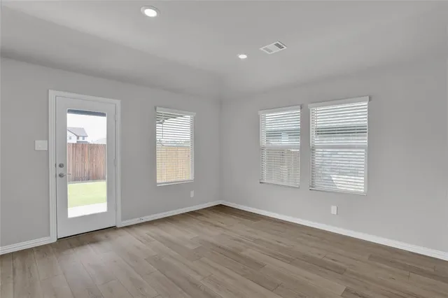 an empty room with wooden floor and windows
