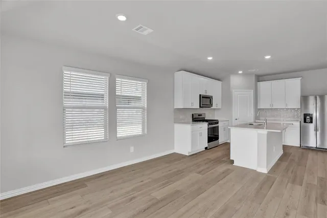 a kitchen with white cabinets and wooden floor