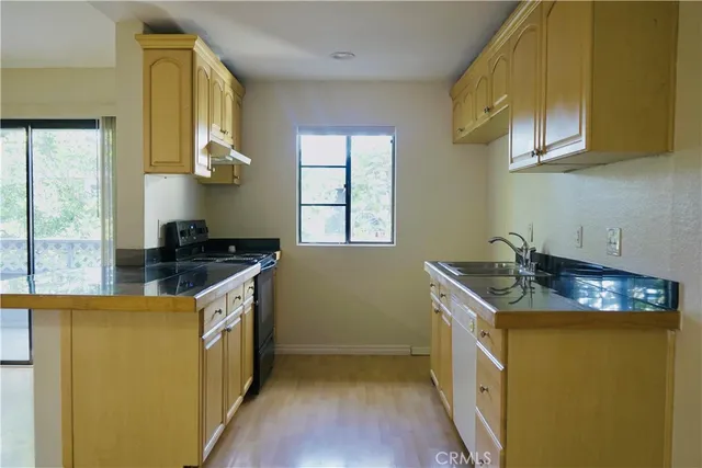 a kitchen with stainless steel appliances granite countertop a sink a stove and a wooden floors