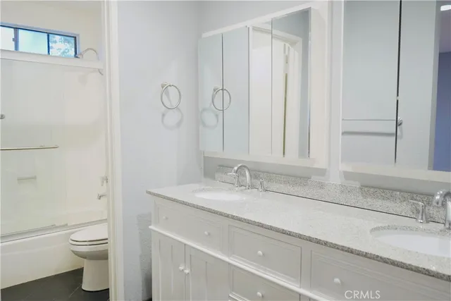 a bathroom with a granite countertop sink a toilet and a mirror