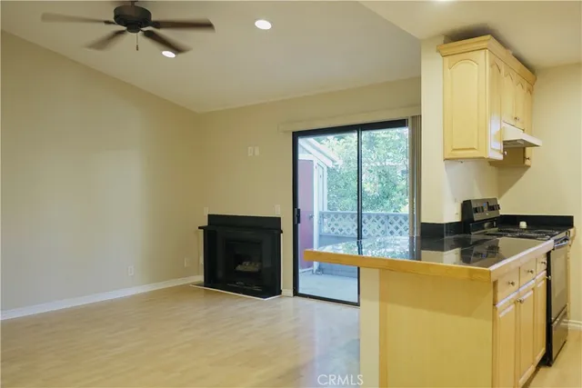 a kitchen with a stove a faucet and a view of living room