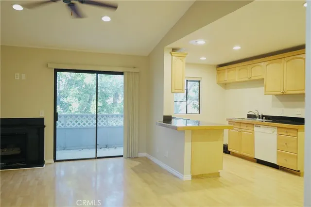 a view of a kitchen with kitchen island wooden floors and stainless steel appliances