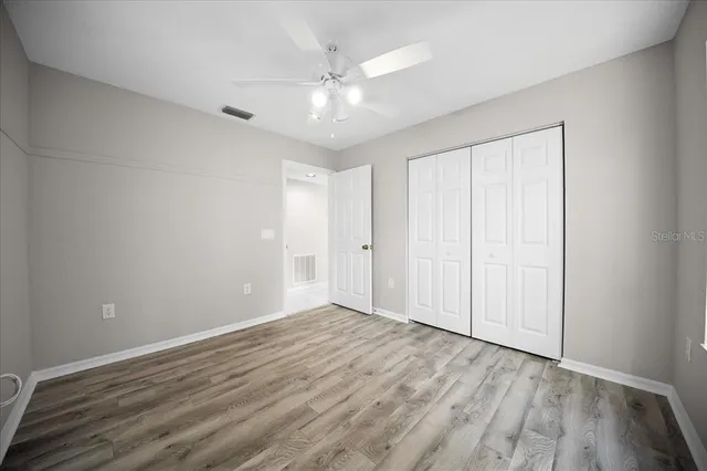 an empty room with windows and fan