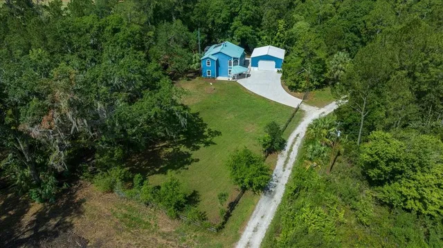 a aerial view of a house with a yard and large trees