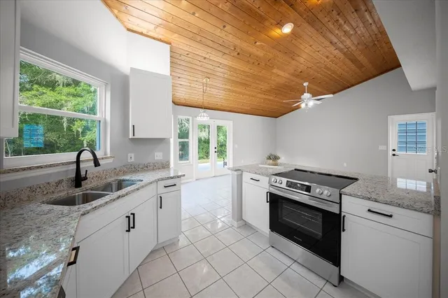 a large kitchen with granite countertop a sink stainless steel appliances and cabinets