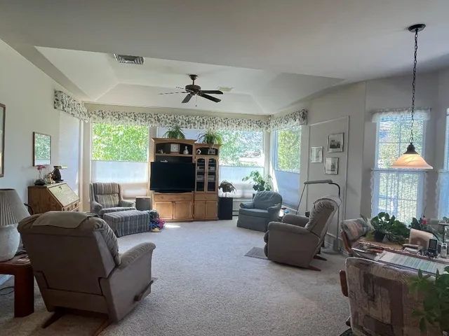 a living room with furniture a ceiling fan and a large window