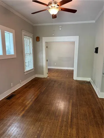 an empty room with wooden floor chandelier fan and windows