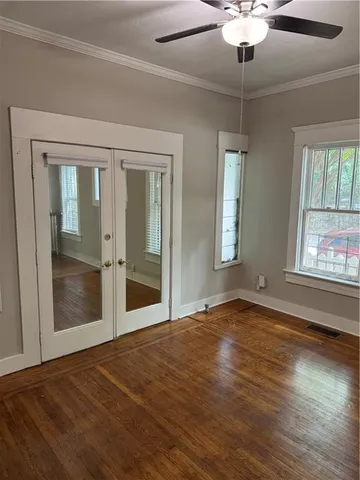 a view of an empty room with window and wooden floor