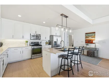 a open kitchen with stainless steel appliances kitchen island granite countertop a dining table chairs and white cabinets